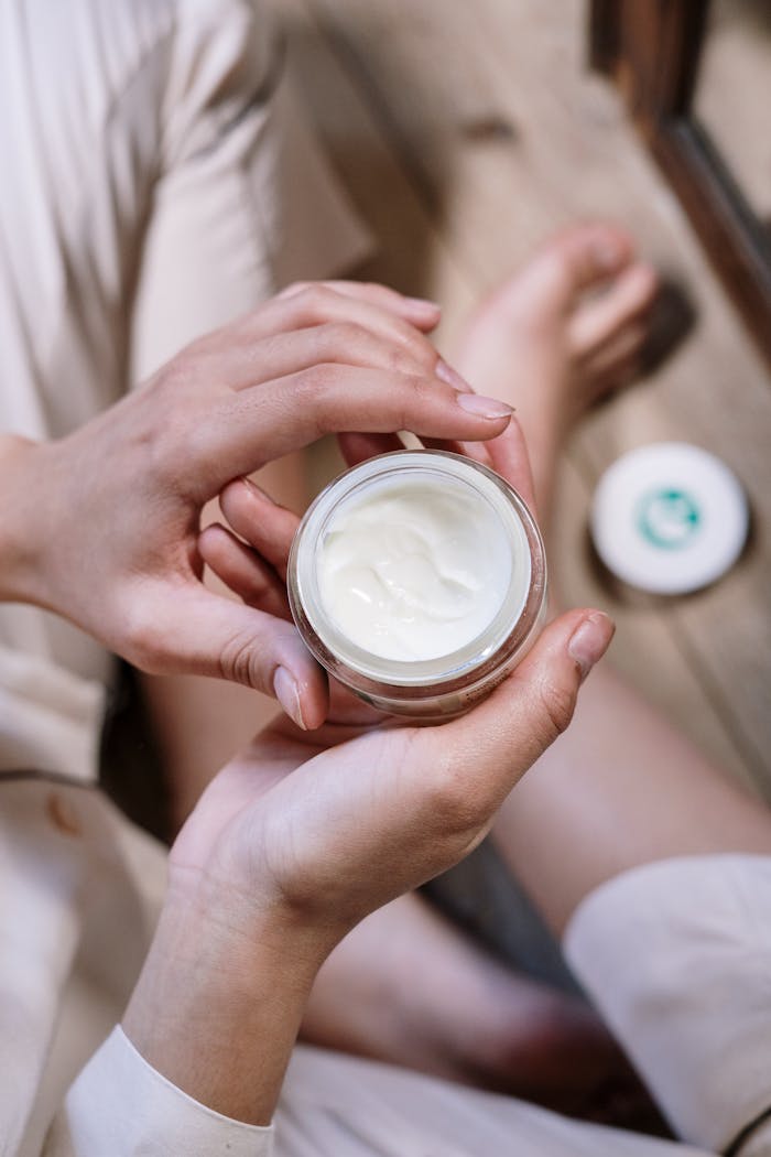 services-06 Close-up of womans hands applying skincare cream during morning routine indoors.