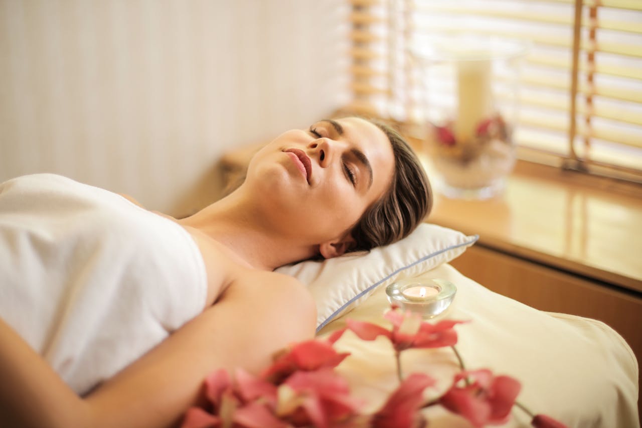 services-09 Woman enjoying a relaxing spa day with flowers and candles indoors.